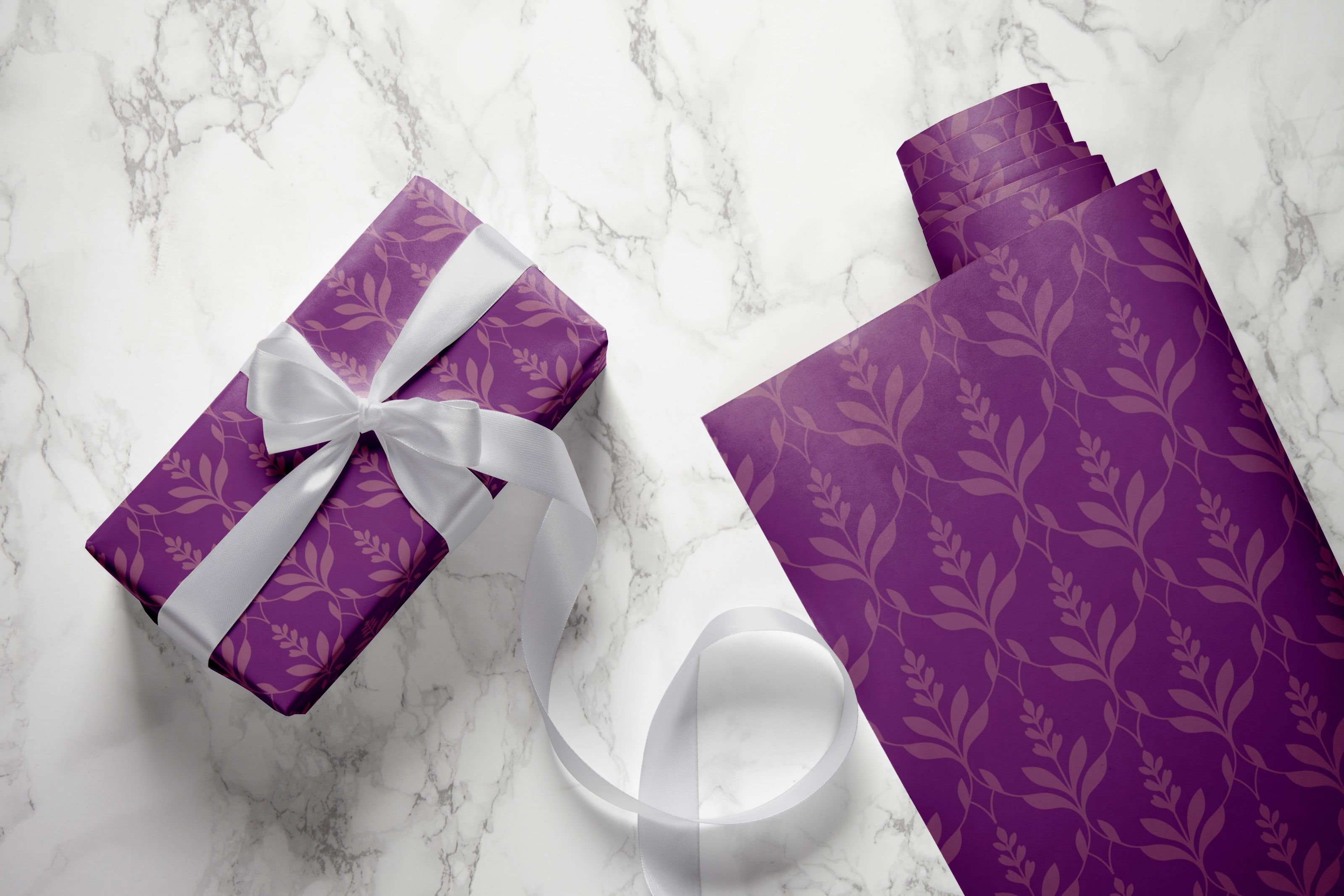 Gift-wrapped box in Zama's purple lattice paper with a white satin ribbon on marble